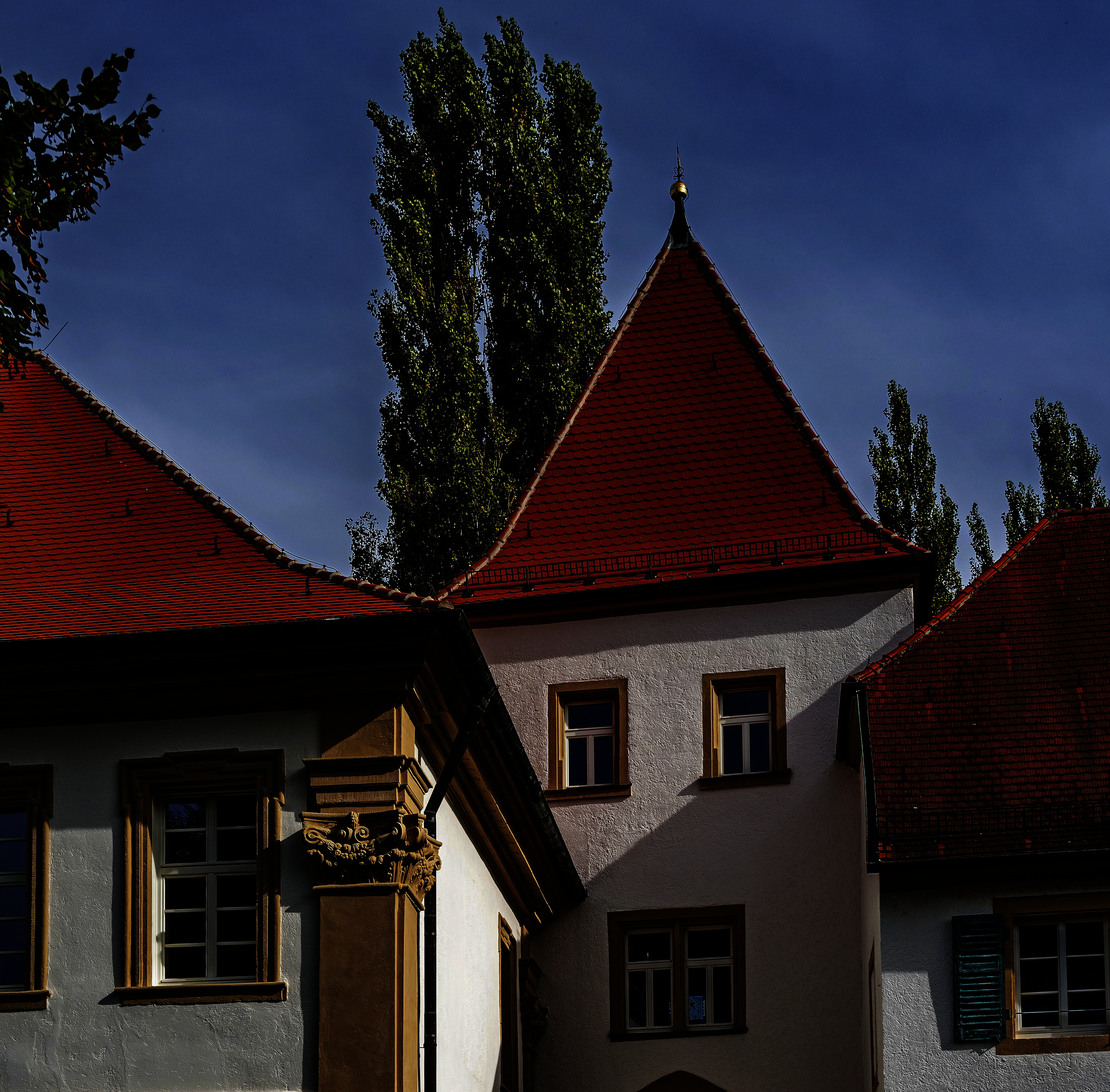 Zwei historische Gebäude, verbunden durch einen zurückgesetzten viereckigen Turm, der eine Unterführung hat.
