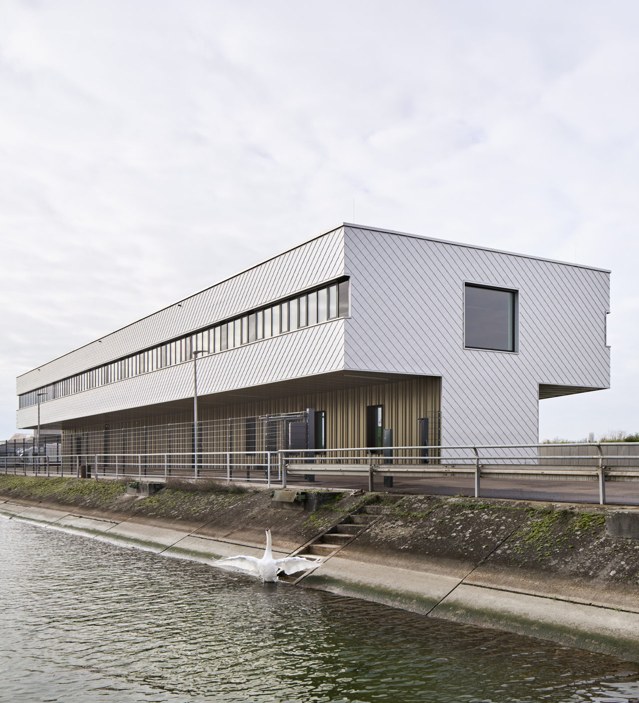 Neubau der Wasserschutzpolizei Kehl am Wasser mit markanter Metallfassade und auskragendem Obergeschoss, davor Uferweg und Geländer.