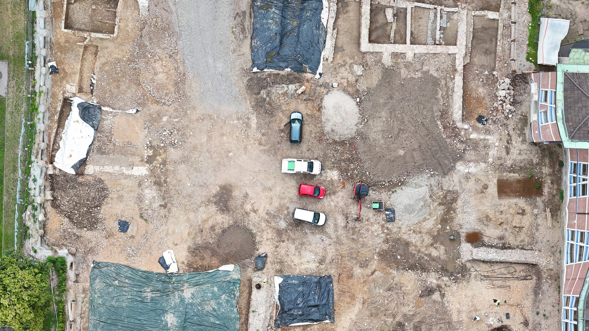 Luftaufnahme der archäologischen Rettungsgrabung an der Habsburgerstraße in Freiburg mit sichtbaren Mauerresten, Abdeckplanen und Baufahrzeugen im August 2025.