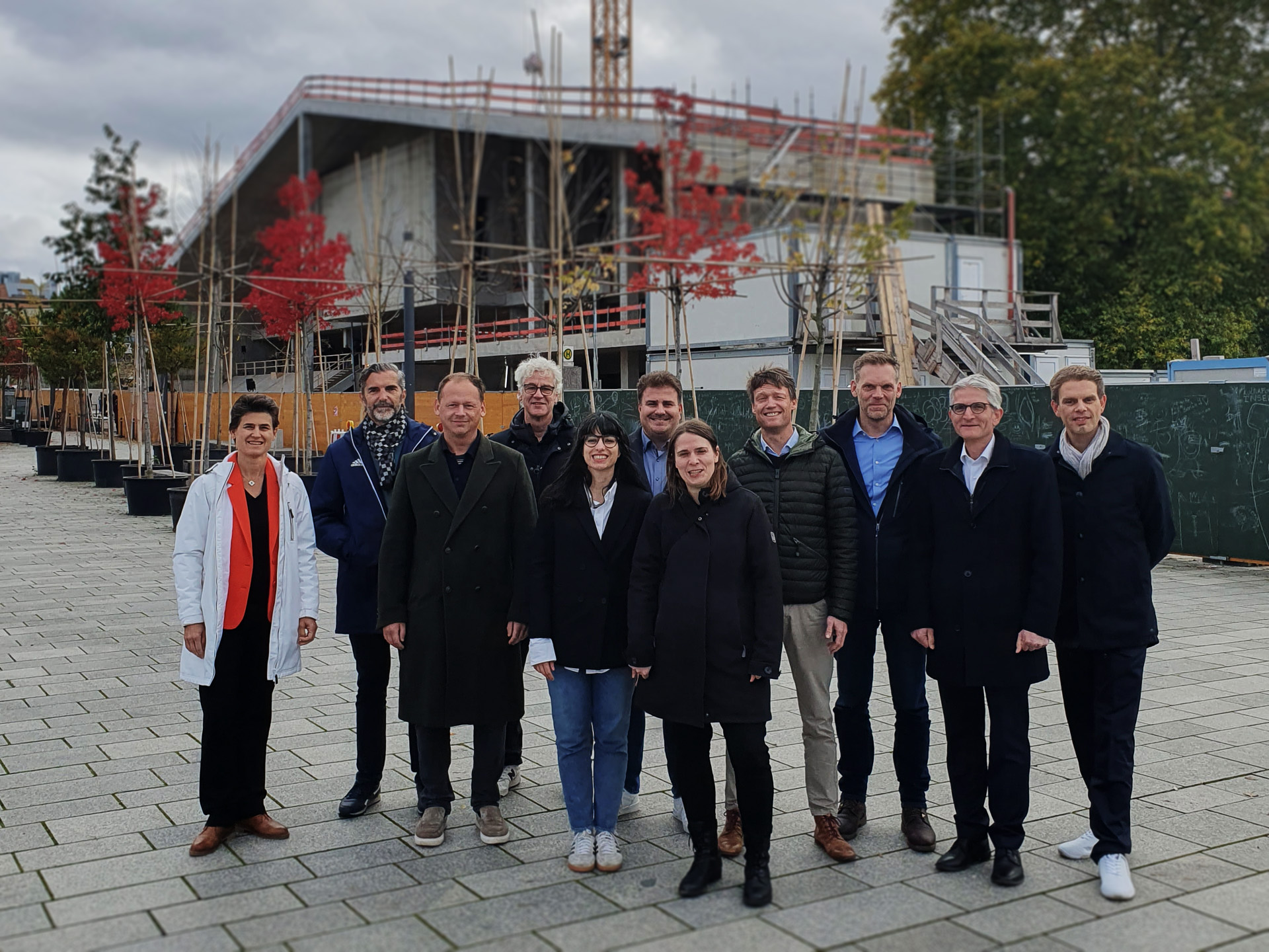 Gruppenbild mit 11 Personen des Projektteams. Sie stehen auf einer gepflasterten Fläche.