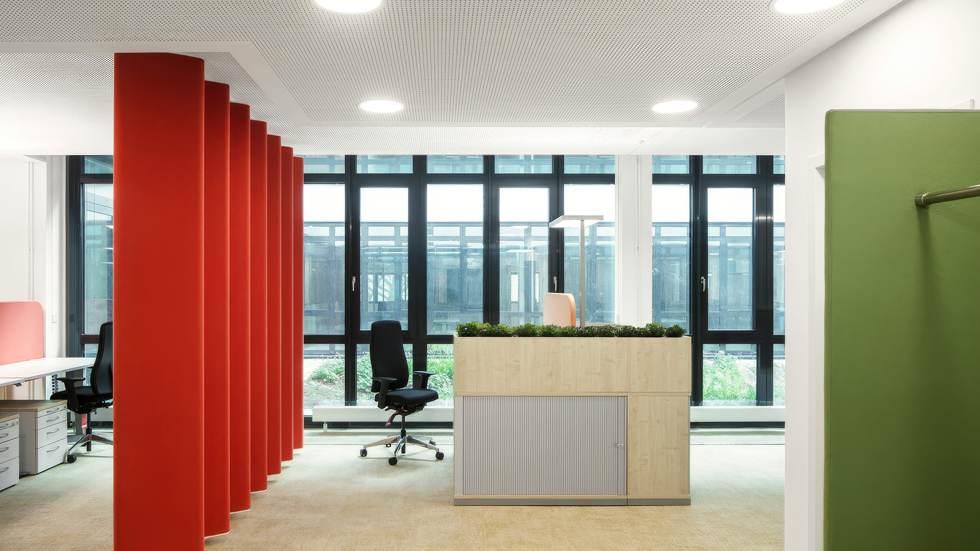 Helle Bürozone im LUBW Neubau mit Pflanzen, farbigen Raumteilern und modernen Arbeitsplätzen. 