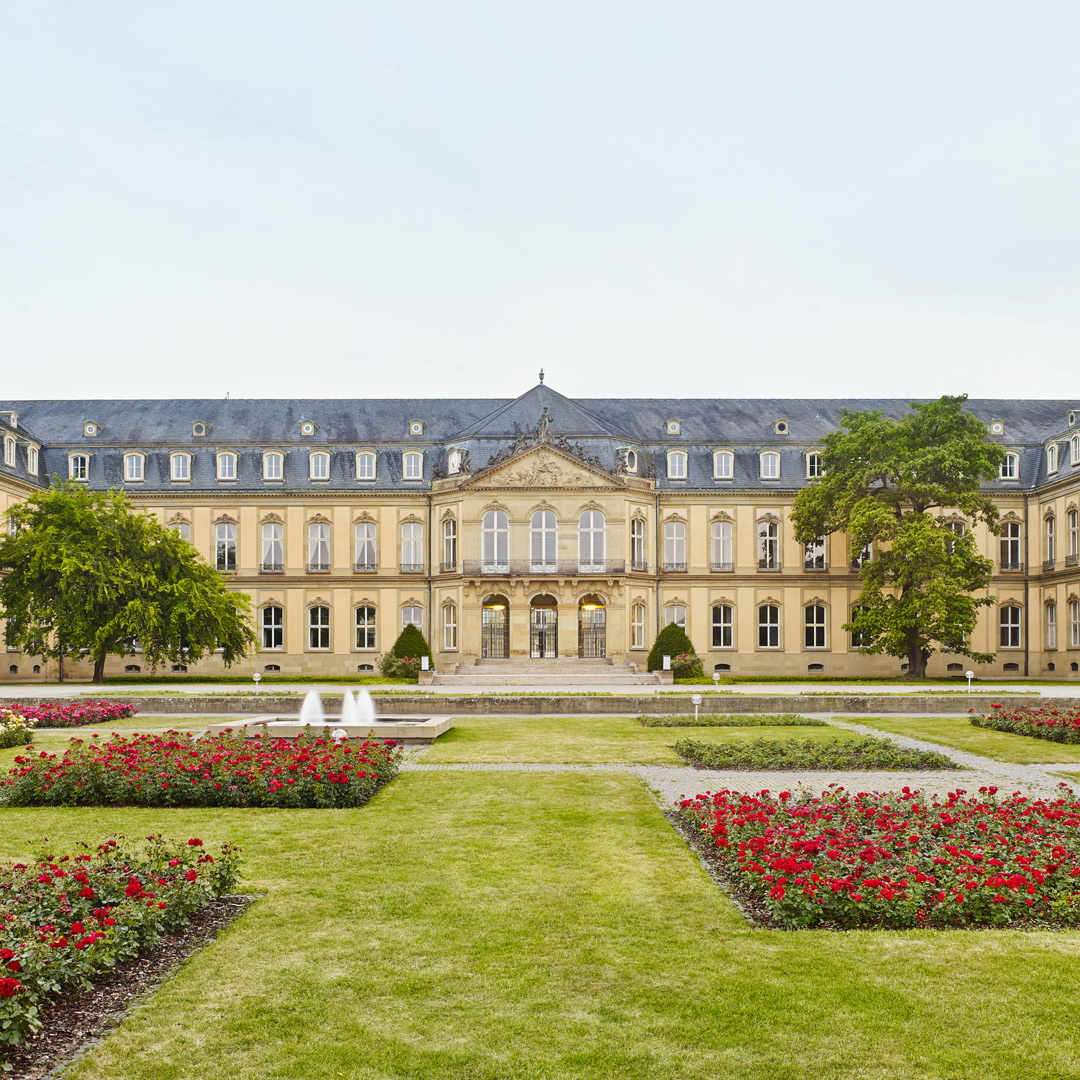 Das Neue Schloss in Stuttgart, davor Rasenflächen, rechteckige Rosenbeete und 2 rechteckige Zierbecken mit Springbrunnen.