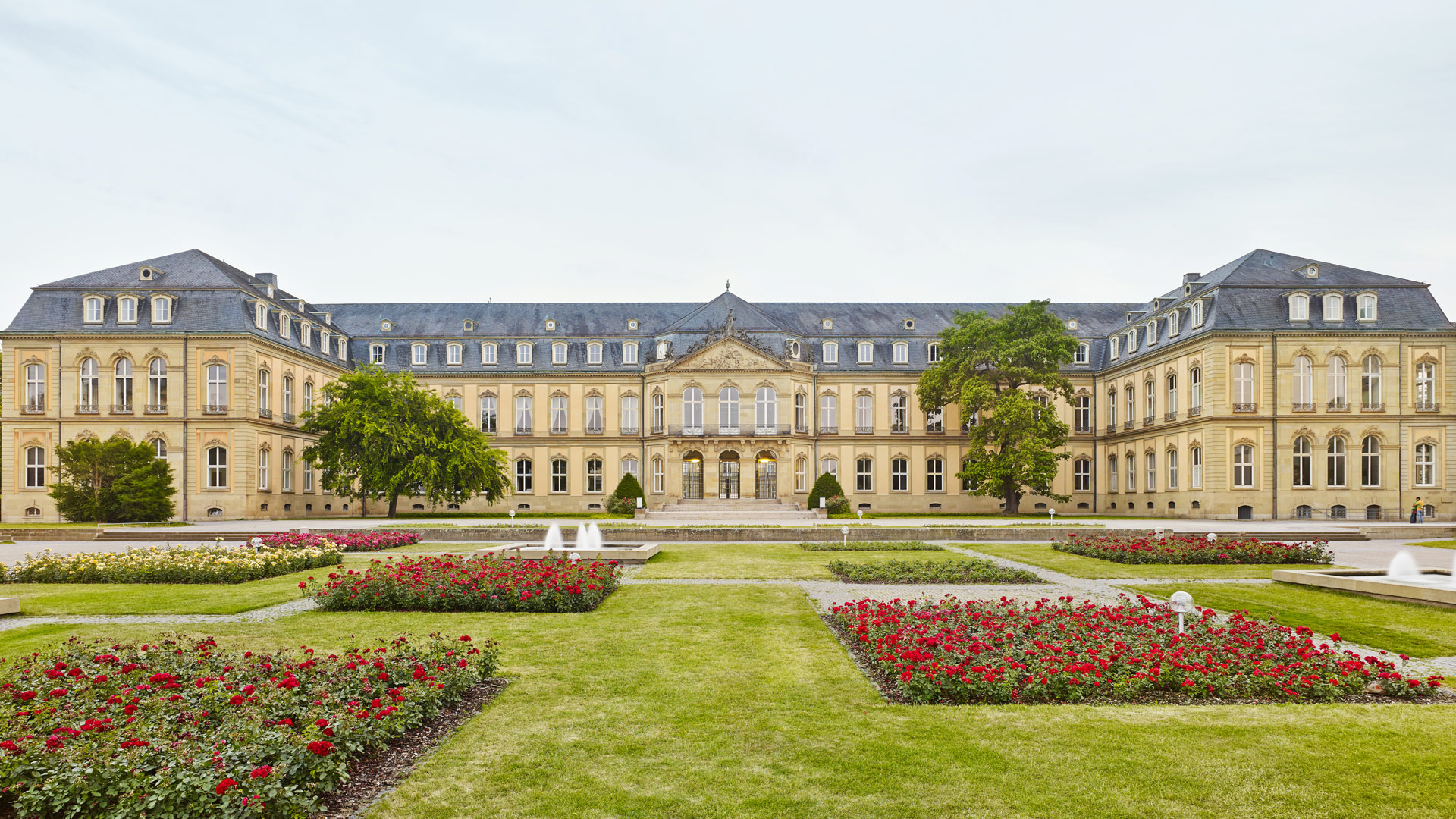 Das Neue Schloss in Stuttgart, davor Rasenflächen, rechteckige Rosenbeete und 2 rechteckige Zierbecken mit Springbrunnen.