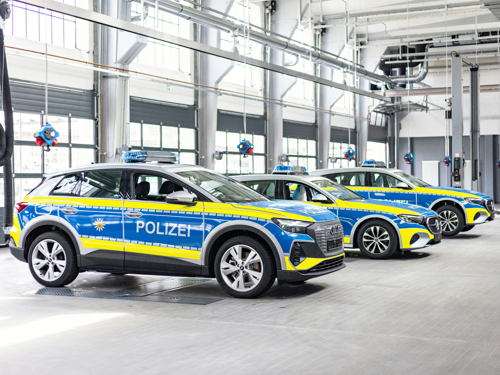 Polizeifahrzeuge in einer sanierten Werkstatt mit moderner Ausstattung, großen Fensterflächen und klar strukturierter Technikzone für Wartungsarbeiten.