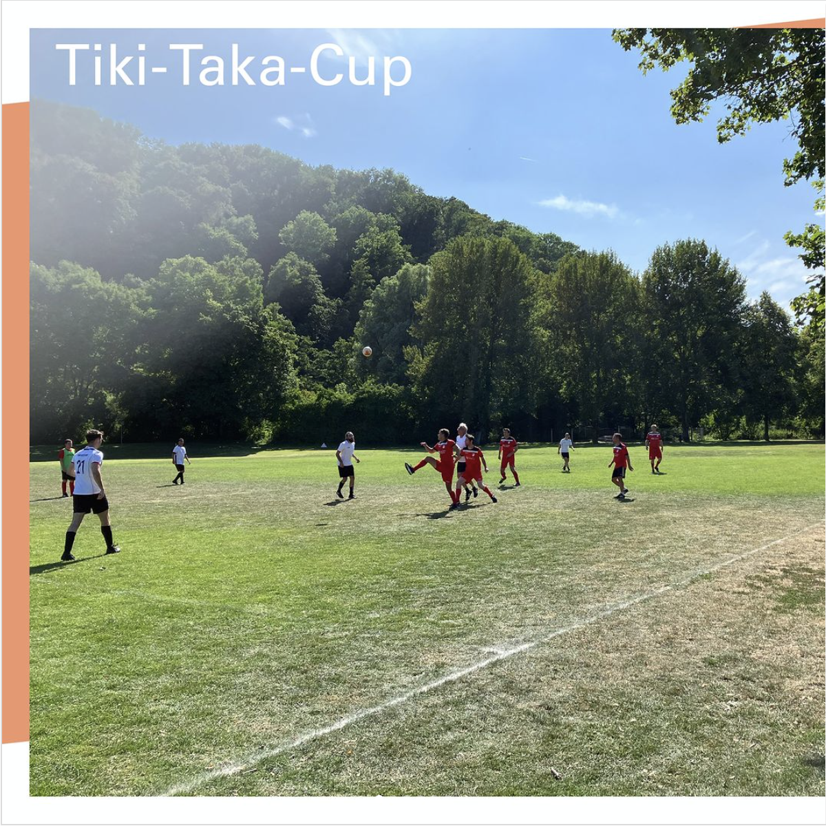 Ein Amateur-Fußballplatz in Mitten eines Waldes, Spieler mit roten und weißen Trikots auf dem Platz.