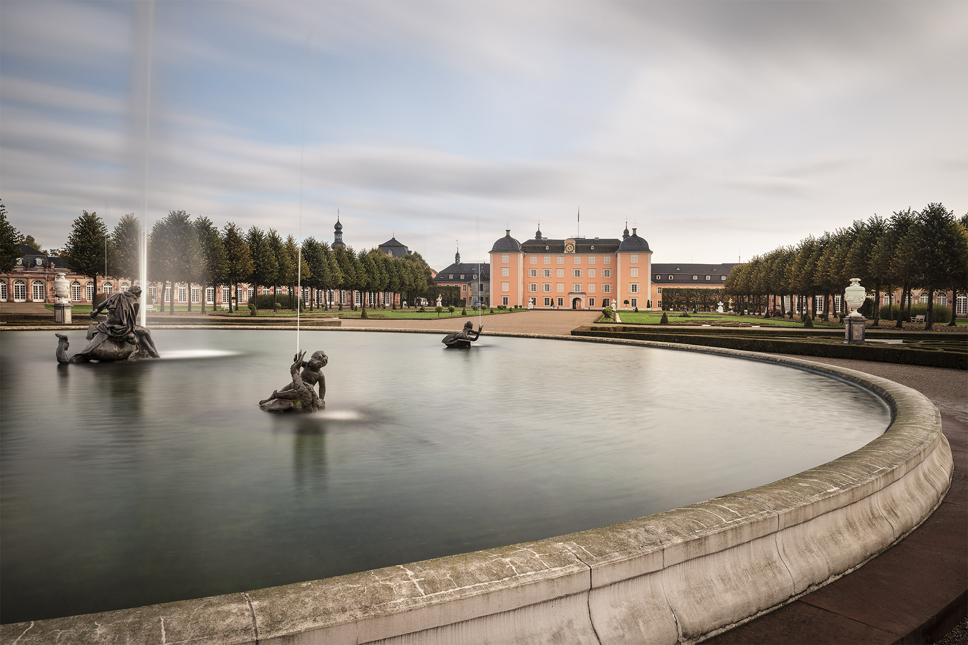 Blick über die Wasserfläche eines Brunnens auf das Schloss Schwetzingen.