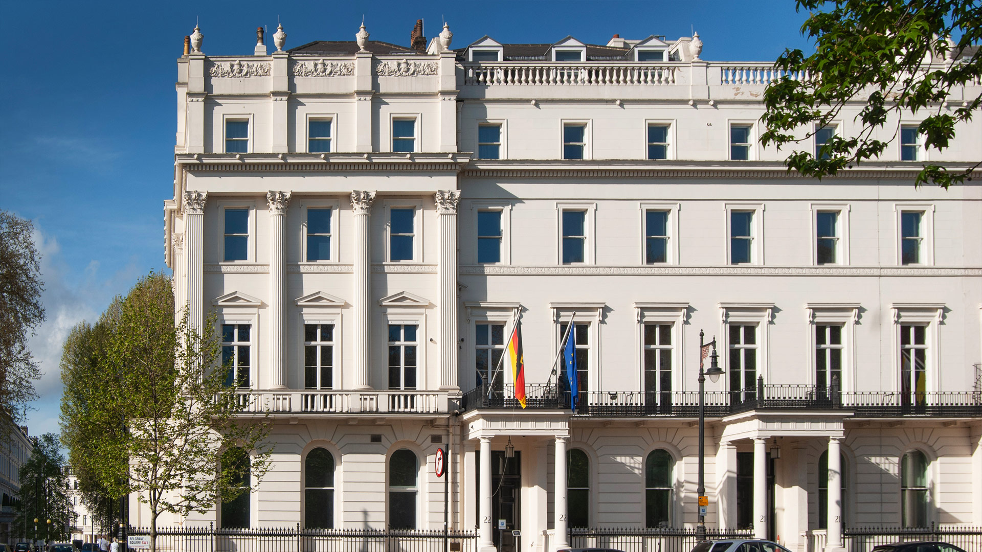 Das weiße, 4-stöckige Gebäude der Botschaft besteht aus Reihenhäusern mit jeweils einem Portikus mit dorischen Säulen.