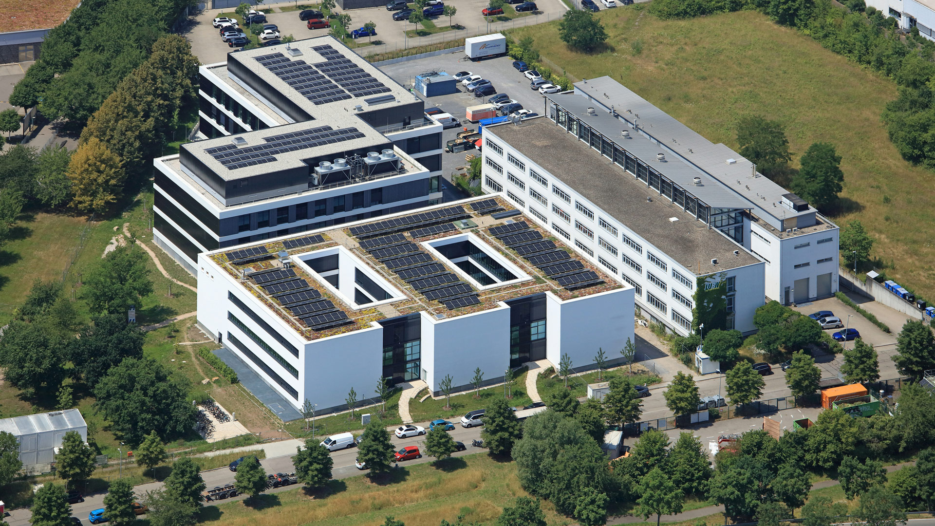Luftbild des Neubaus der Landesanstalt für Umwelt. Auf dem Dach sind Solaranlagen, die Gebäude sind umgeben von Grünflächen.