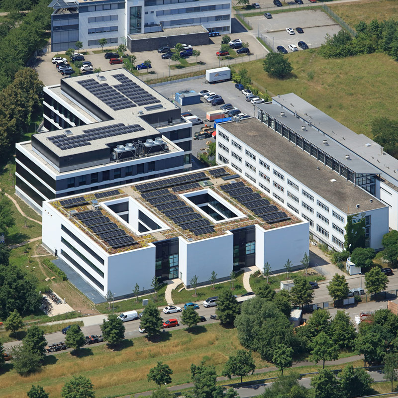 Luftbild des Neubaus der Landesanstalt für Umwelt. Auf dem Dach sind Solaranlagen, die Gebäude sind umgeben von Grünflächen.