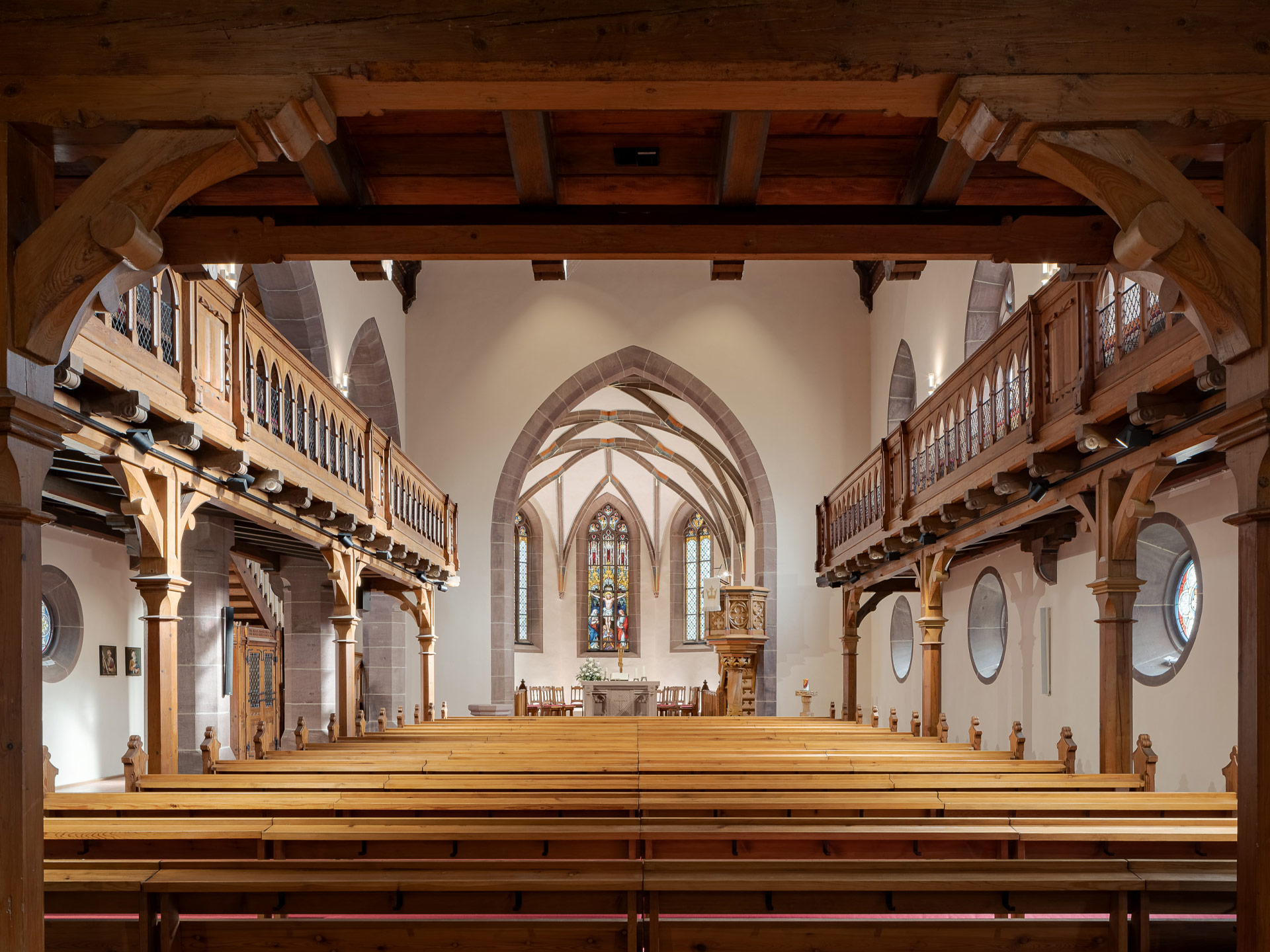 Das Innere von St. Blasius, der Blick über die Kirchenbänke hinweg Richtung Altar, rechts und links holzgestützte Seitenemporen.